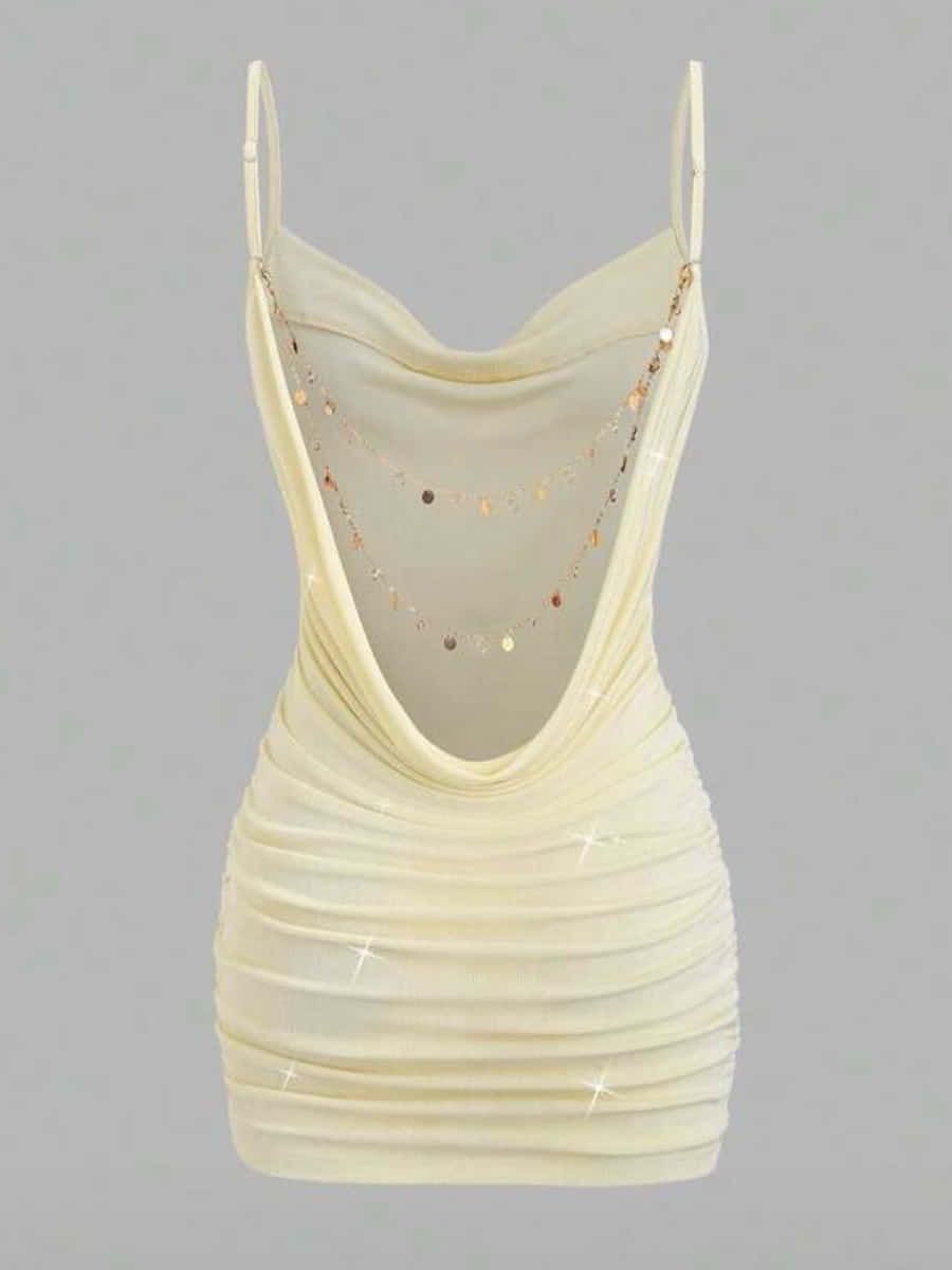 Vestido corto color crema drapeado, con espalda descubierta y dos cadenitas doradas de monedas